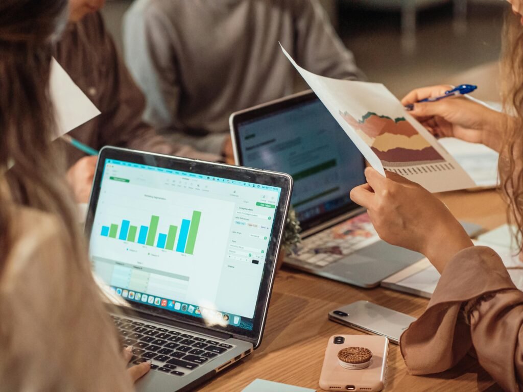pexels-photo-7651734-7651734 A group engaged in a business meeting analyzing charts on laptops and papers.